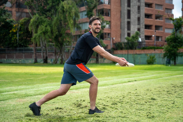 istock Young man throwing frisbee puck at the public park 1592653896