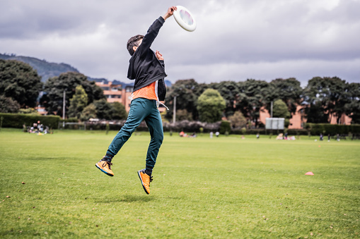 Boy jumping to catch a frisbee at the public park