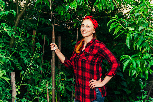 A girl in a red bandana and shirt is harvesting in the garden and vegetable garden