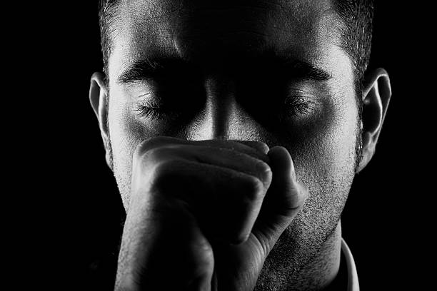 istock Man with fist and eyes closed on black background 159269140