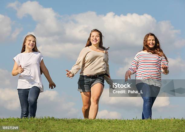 Tres Niñas Sonriendo Ejecución En Verde Hierba Foto de stock y más banco de imágenes de Adolescente - Adolescente, Aire libre, Amistad