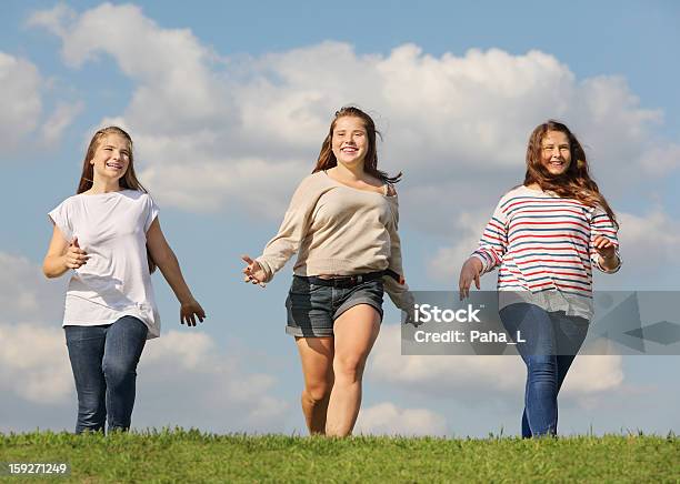 Três Sorridente Meninas Execução Na Relva Verde - Fotografias de stock e mais imagens de Adolescente - Adolescente, Amizade, Amizade feminina