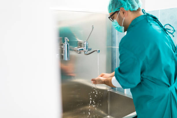 istock Male surgeon washing hands under running water before surgery 1592716094