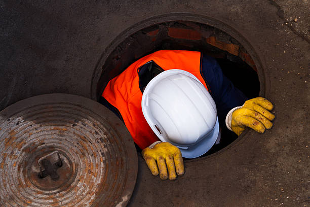 Down The Manhole A Worker, man going down to work in sewage. manhole stock pictures, royalty-free photos & images