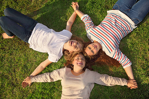 istock Three happy girls hold hands and lie on grass 159274938