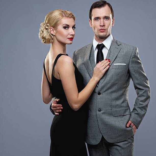 A retro couple looking at the camera on a gray background stock photo