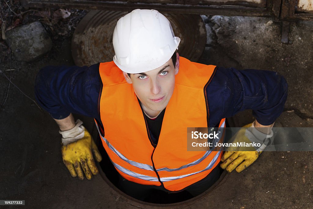 Trabajador en tapadera de cloaca - Foto de stock de Boca de alcantarilla libre de derechos