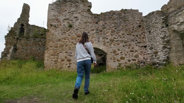 Girl goes to the old dilapidated castle. Slow motion.