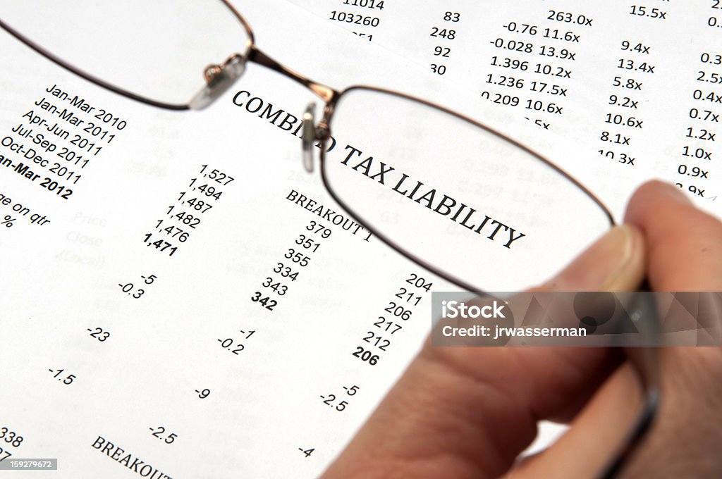 Ręka trzyma szkło powiększające Wyświetlono słowa zobowiązań podatkowych - Zbiór zdjęć royalty-free (Formularz podatkowy)