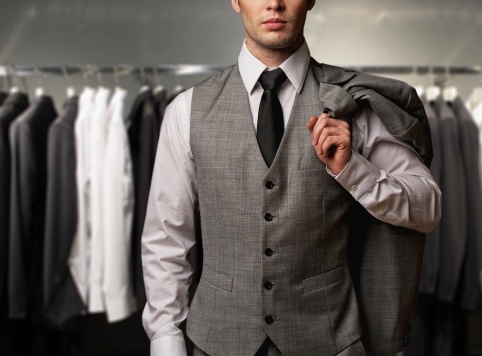 Businessman wearing classic vest against row of suits in shop