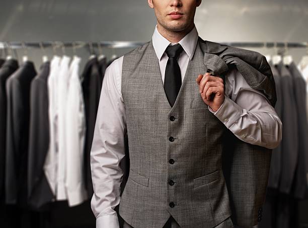 Businessman wearing classic vest against row of suits in shop stock photo