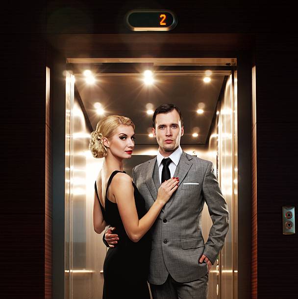 retro casal de pé contra elevador - retro revival couple men elegance imagens e fotografias de stock
