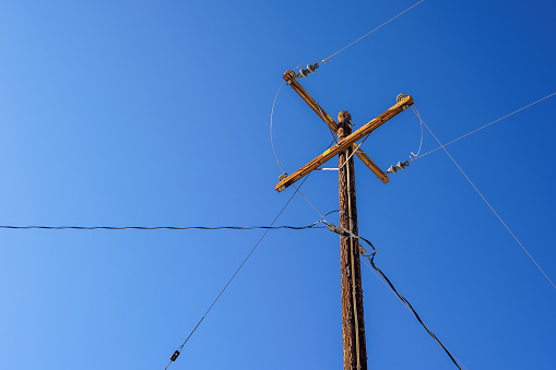 An old wooden electrical pole with wires and a clear blue sky in Joshua Tree, California.