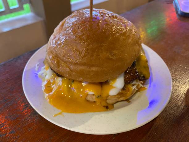 istock Burger with melting cheddar cheese and bacon centralized on a brown background. 1593030951