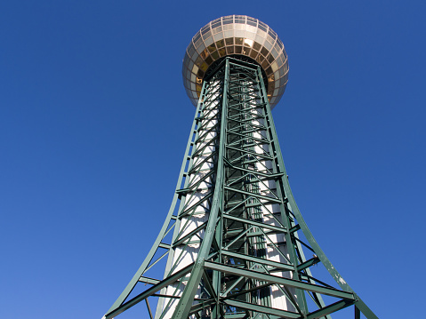Against a clear blue sky, the Sunsphere Tower in Knoxville, Tennessee, USA, stands tall and captivating with its golden globe as viewed from below.