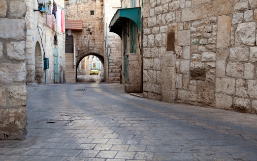 Stone city street and stone buildings on Star Street in the West Bank town of Bethlehem. A Palestinian taxi is in the distance.