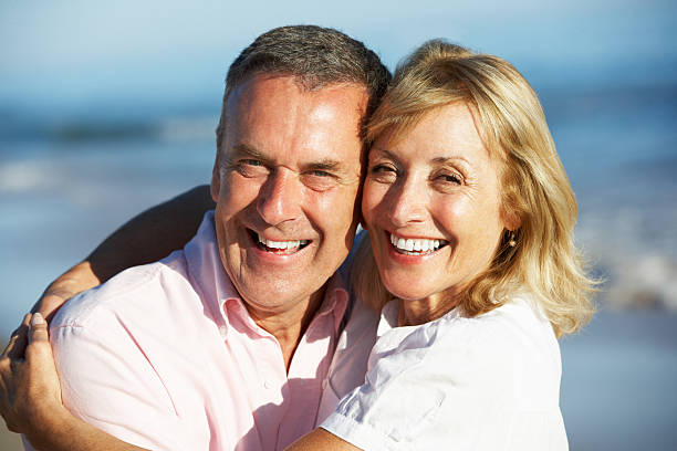 istock Senior couple on a beach hugging and smiling with joy 159315485