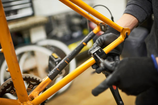istock Repair of a bicycle: person disassembling an orange bike in his workshop 1593160179
