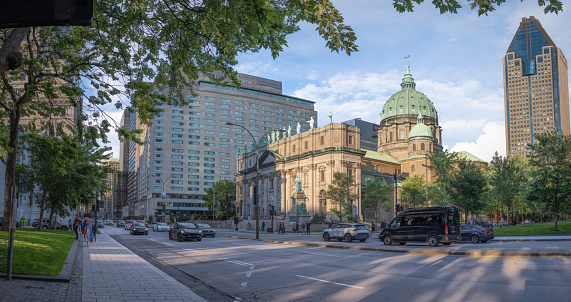 Montreal, Quebec, Canada - July 29, 2023:  The downtown Montreal skyline as seen from Place du Canada Park.  In the foreground is Mary Queen of the World Church.  In the background left is the Fairmont Queen Elizabeth Hotel.