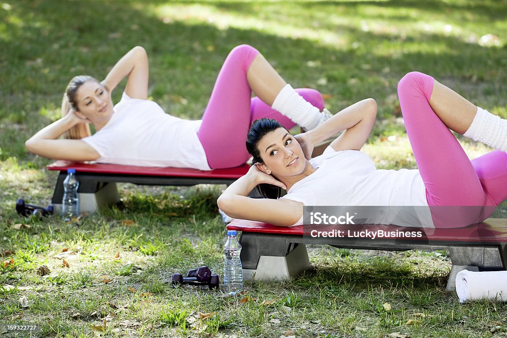 Women exercise in park Young women exercising doing sit-ups in the park Abdominal Muscle Stock Photo