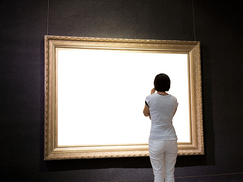 woman looking at white frames in an art gallery.