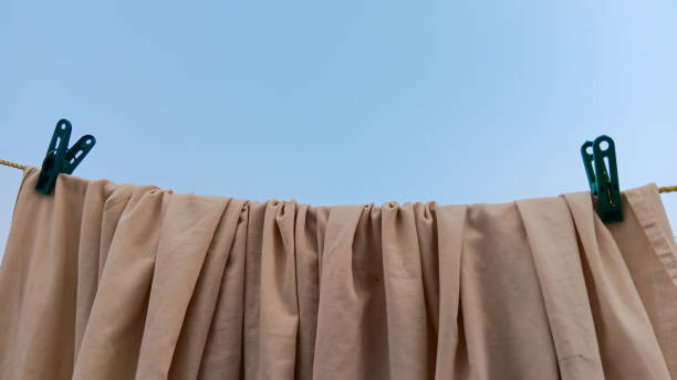 istock A curtain cloth clip that is on a  clothesline with a blank plain blue background 1593276418