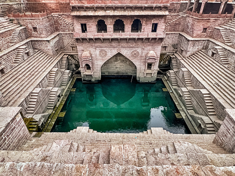 A wide view of the Toorji Ka Jhalra Bavdi stepwell (a bavdi or baori) that is located in the center of the city of Jodhpur in Rajasthan. The deep well is surrounded by rows of steps.