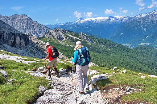 Senior couple hiking in Brenta Dolomites, Italy with rocky landscape in the background