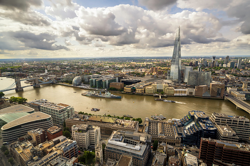 A London aerial panoramic view of the busy city during the day with clouds, a cloudscape. The wide angle captures the hustle and bustle of a large city and daily city life. The London skyline is spectacular with the modern glass skyscrapers and traditional British buildings, architecture. London is the urban capital city of England and is a popular tourist travel destination in Great Britain, UK.