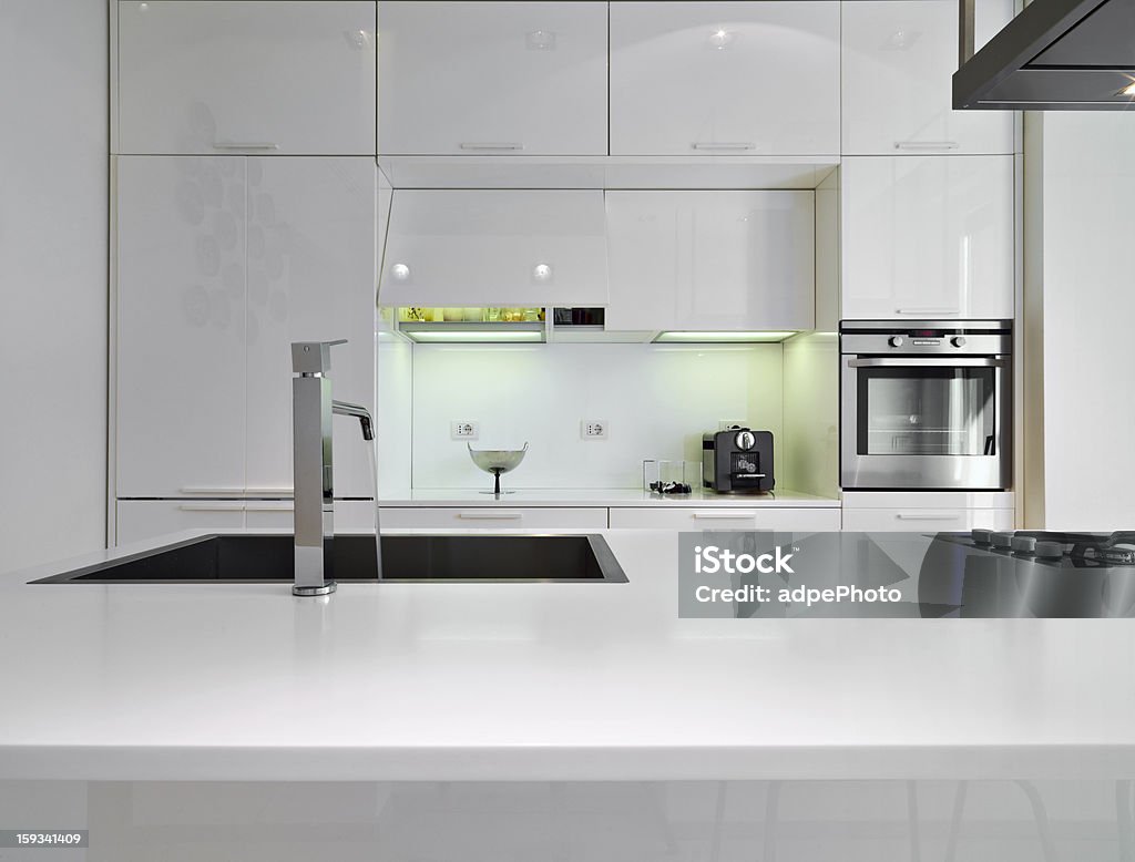 modern white kitchen detail of sink in a white modern kitchen with steel faucet and oven Apartment Stock Photo