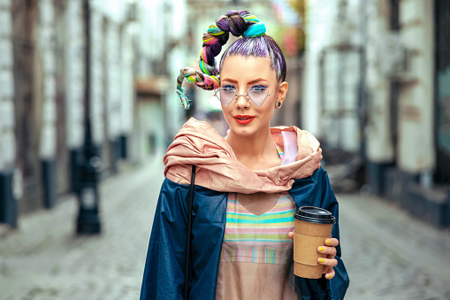 Cool funky young girl with piercing and crazy hair enjoy takeaway coffee on street