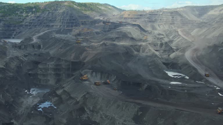 Various huge machines work at open pit coal mine, aerial footage.