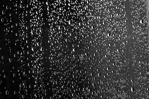 Glass wall of shower at bathroom with water drops and natural light in black and white. Photo taken August 5th, 2023, Zurich, Switzerland.