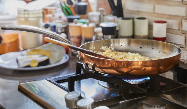 les oignons hachés sont frits dans une casserole en cuivre au feu de gaz - copper pans photos et images de collection