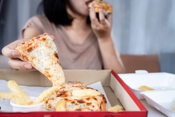 binge-eating-störungskonzept mit frau über fast-food-pizza - bulimia stock-fotos und bilder