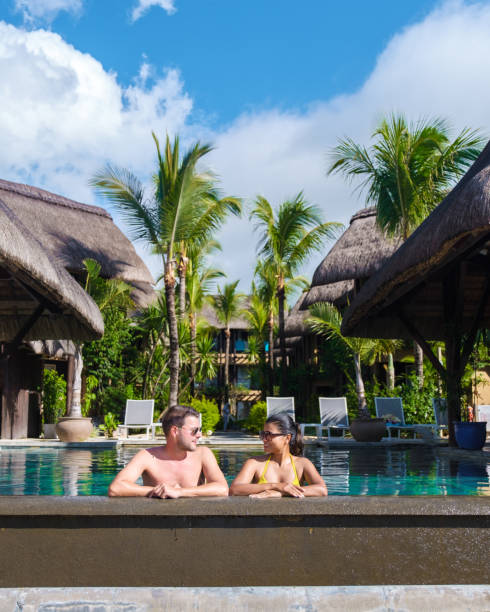 man and woman relaxing in a swimming pool, a couple on a honeymoon vacation in mauritius - honeymoon beach swimming pool couple imagens e fotografias de stock