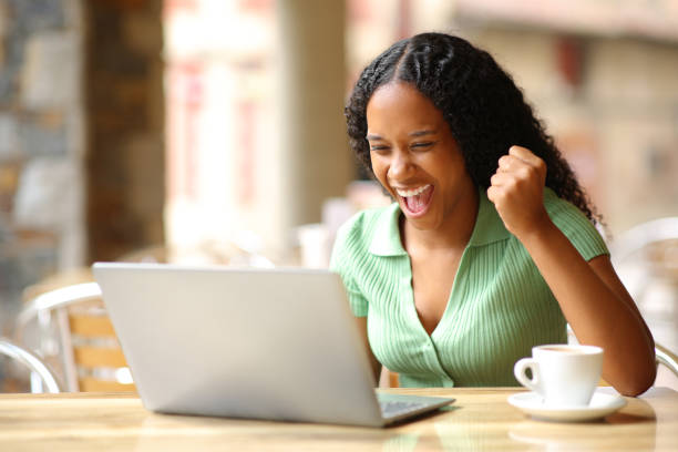 istock Excited black woman checking laptop in a bar 1593627996