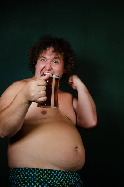 istock Funny fat man drinks beer on an Irish holiday. 1593628374
