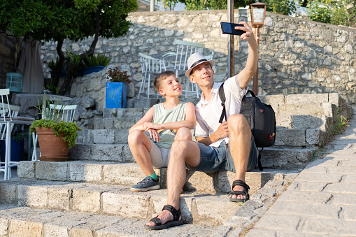 Father and son are exploring beautiful small Greek village Afytos on Chalkidiki. They are taking selfie.