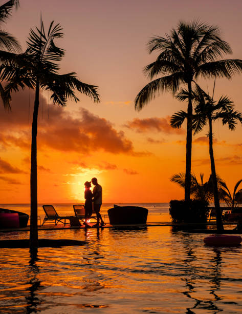 man and woman relaxing in a swimming pool, a couple on a honeymoon vacation in mauritius - honeymoon beach swimming pool couple imagens e fotografias de stock