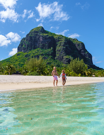 Man and Woman on a tropical beach in Mauritius, a couple on a honeymoon vacation in Mauritius Le Morne Beach with Le Morne Mountain on the background