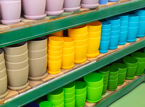 Empty flower pots in a store or greenhouse. Ceramic or plastic flower pots at the shop. Colorful flower pots on the shelf in the store. Colorful pots for plants.