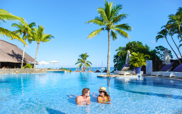 man and woman relaxing in a swimming pool, a couple on a honeymoon vacation in mauritius - tropisch-motief-fotos stockfoto's en -beelden