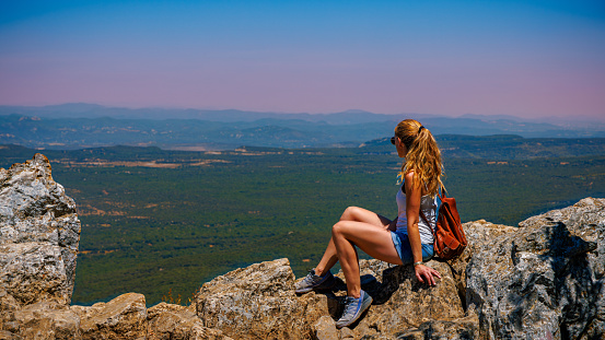 Woman sitting on mountain peak enjoying panoramic view of France landscape- hiking, adventure, travel concept