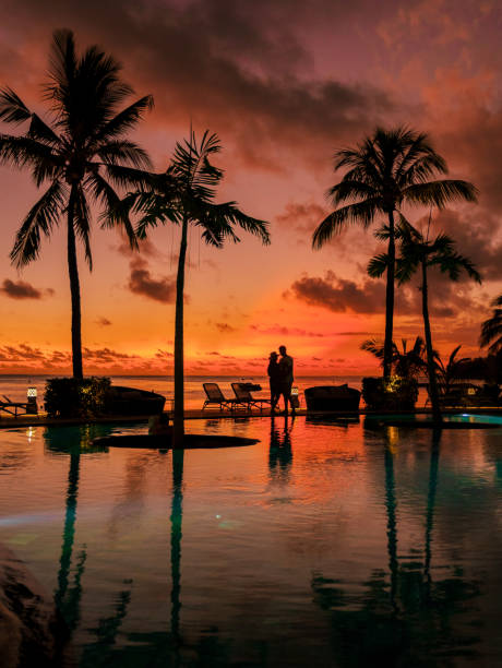 man and woman relaxing in a swimming pool, a couple on a honeymoon vacation in mauritius - honeymoon beach swimming pool couple imagens e fotografias de stock