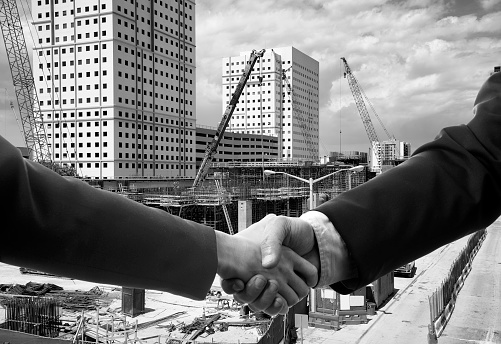 Two engineers handshaking in construction site, Miami, Florida.