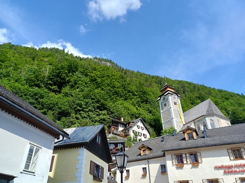Hallstatt, Austria - June 7, 2023: House on the mountainside in Hallstatt town, with blue sky clouds in background.
