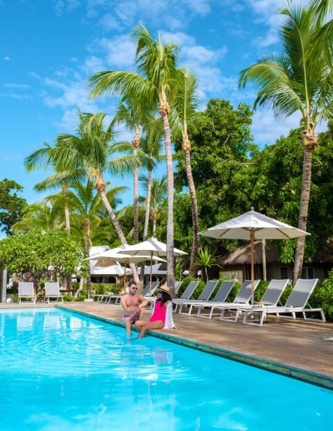 man and woman watching sunrise by a swimming pool, a couple on a honeymoon vacation in mauritius - honeymoon beach swimming pool couple imagens e fotografias de stock