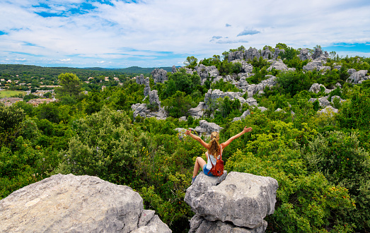 Happy woman standing in rock enjoying beautiful landscape panorama view of rock formation in France- Gard, Sauve, La mer des rochers- Travel, tourism, adventure concept