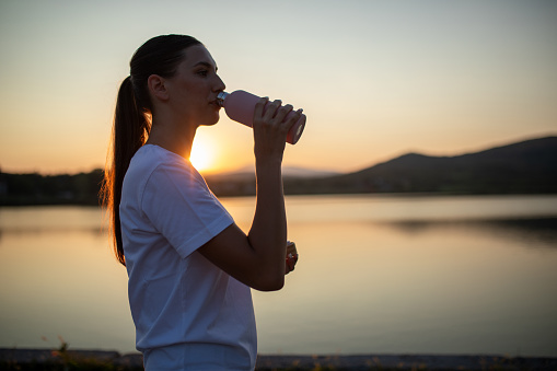 Young beautiful woman drinking water after running from metal water bottle